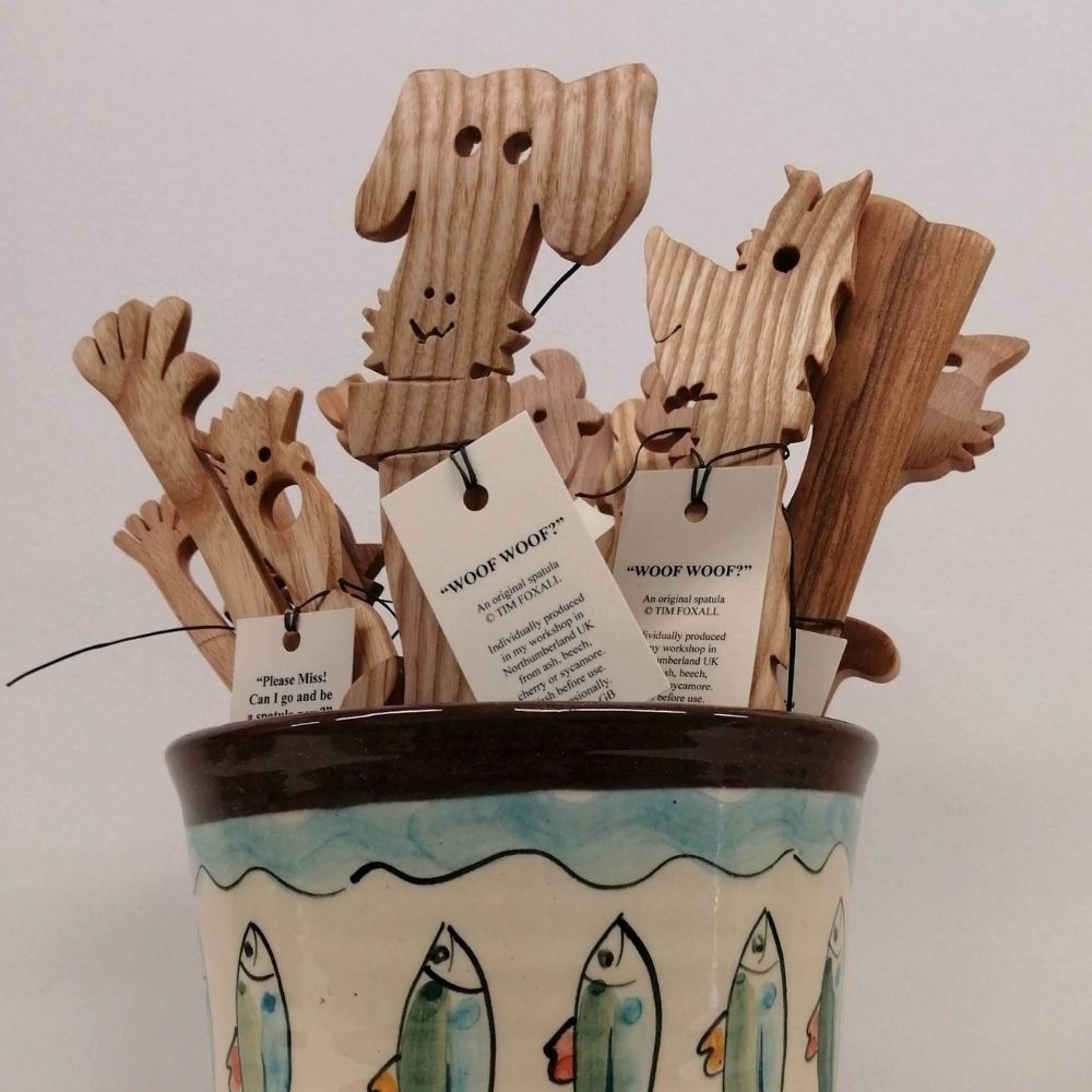 Handmade wooden dog-shaped bookmarks displayed in a ceramic pot with hand-painted fish decoration.