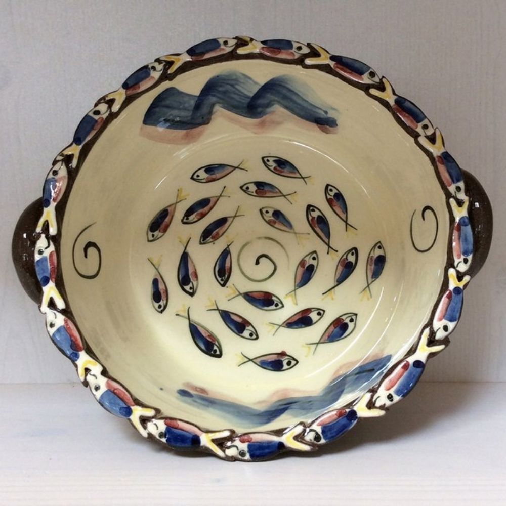 Handmade ceramic bowl with painted fish designs, wave details and decorative handles on a cream glazed finish.