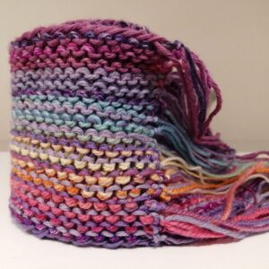 Close-up of a colourful hand-knitted scarf with pink, purple, blue, yellow and orange stripes and tassel ends.