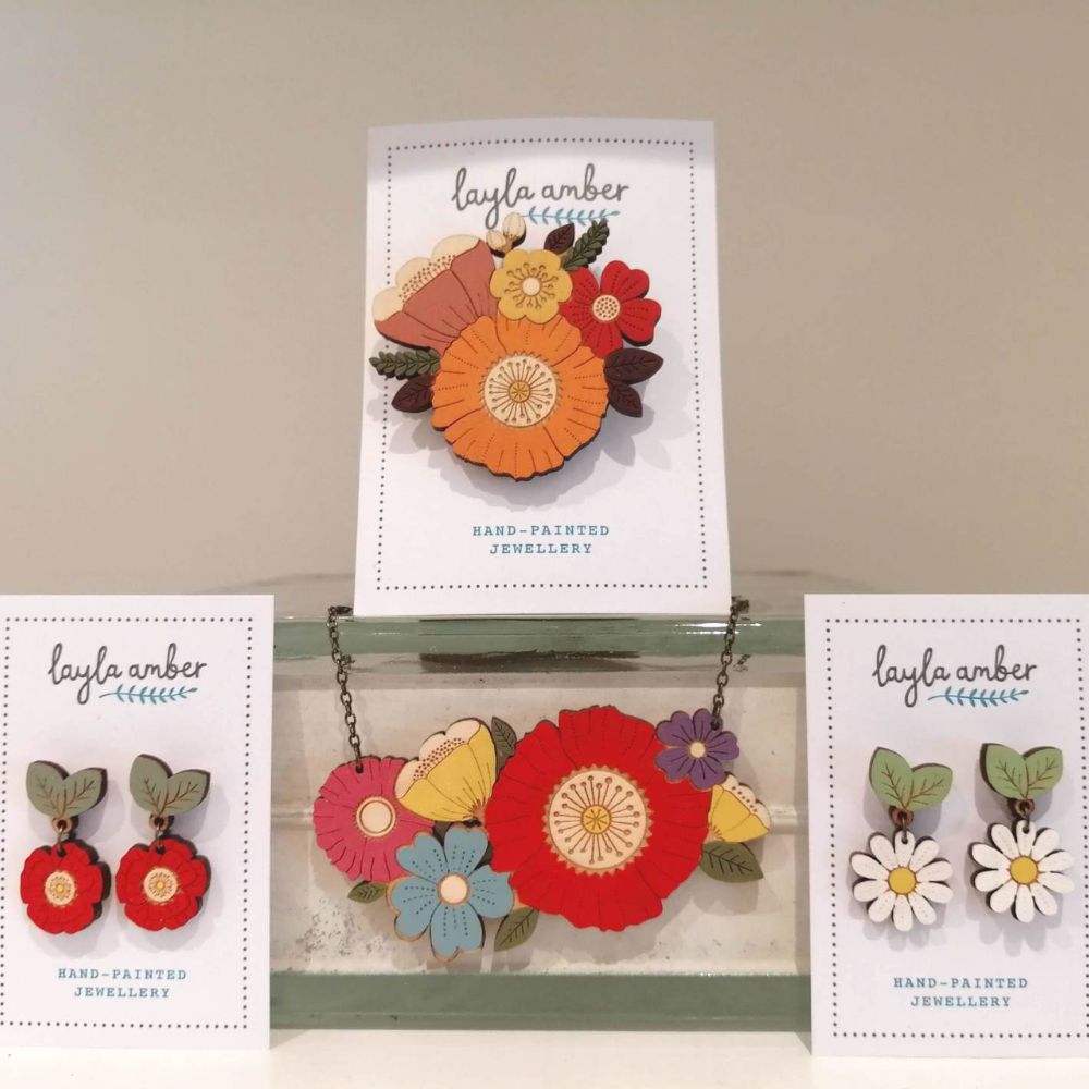 Display of Layla Amber hand-painted floral jewellery, including colourful flower earrings, brooches and a statement necklace.