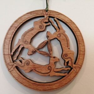 Round laser cut wooden hanging decoration featuring several hares running in a circular design.