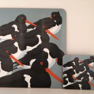 Matching placemat and coaster set featuring illustrated black and white oystercatcher birds with orange beaks.