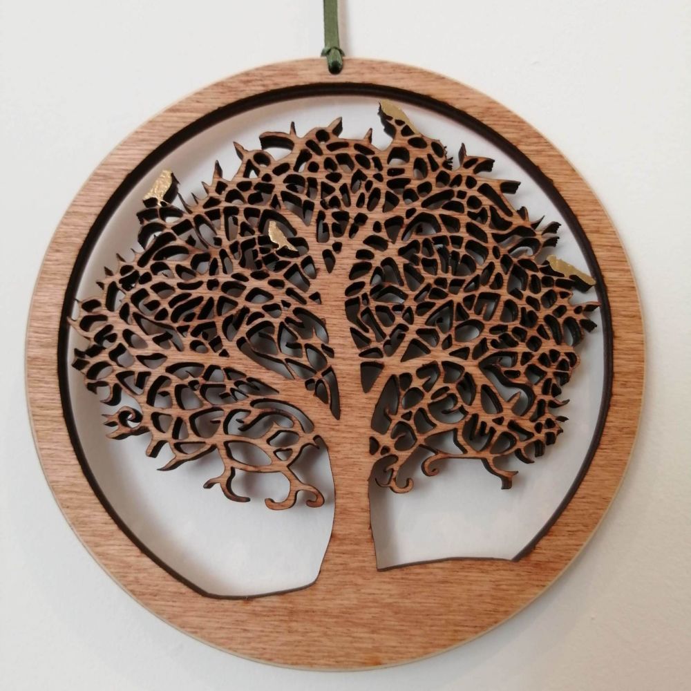 Round laser cut wooden tree of life hanging decoration with detailed branches and leaves.