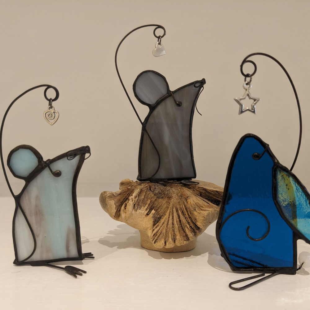 Handmade stained glass mouse decorations in pale grey and blue tones with wire tails, hanging charms and natural wood display details.