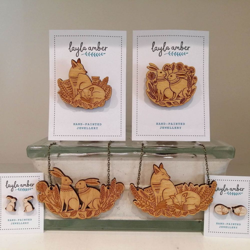 Display of Layla Amber hand-painted wooden jewellery featuring fox, rabbit and woodland animal designs on cards and necklaces.